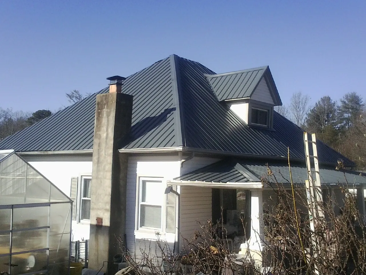 Dark blue standing seam metal roof on a white farmhouse with dormer — Slate & Tile Roof Repair by Roofing Brothers in Noblesville