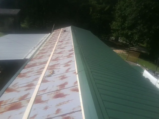 Old rusted panels beside newly installed green metal roofing — Wind Damage Roof Repair by Roofing Brothers in Noblesville