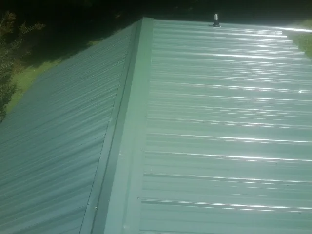 New green metal panels meeting at the ridge of a roof — Flat Roof Repair work by our crew in Noblesville