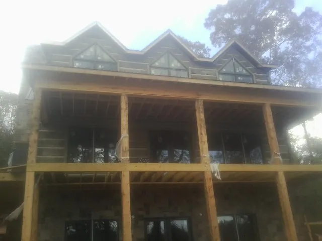 Dormers and porch framing on a large log home under construction — Roof Coating work by our crew in Noblesville