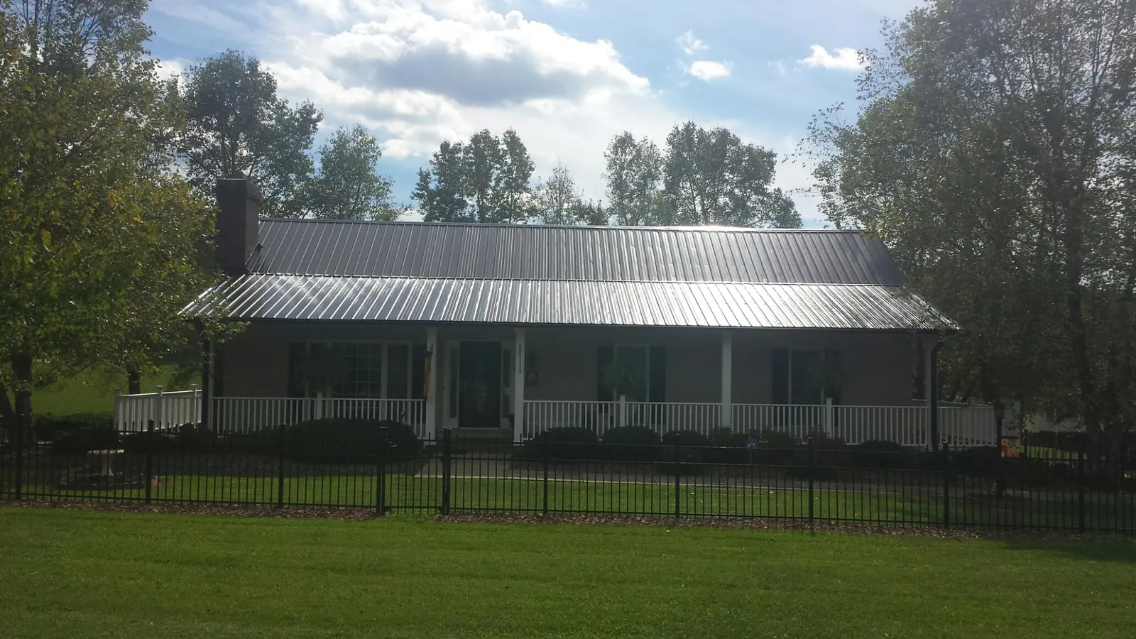 Gray metal roof on a brick ranch with a full width front porch — Gutter Guard Installation work by our crew in Noblesville