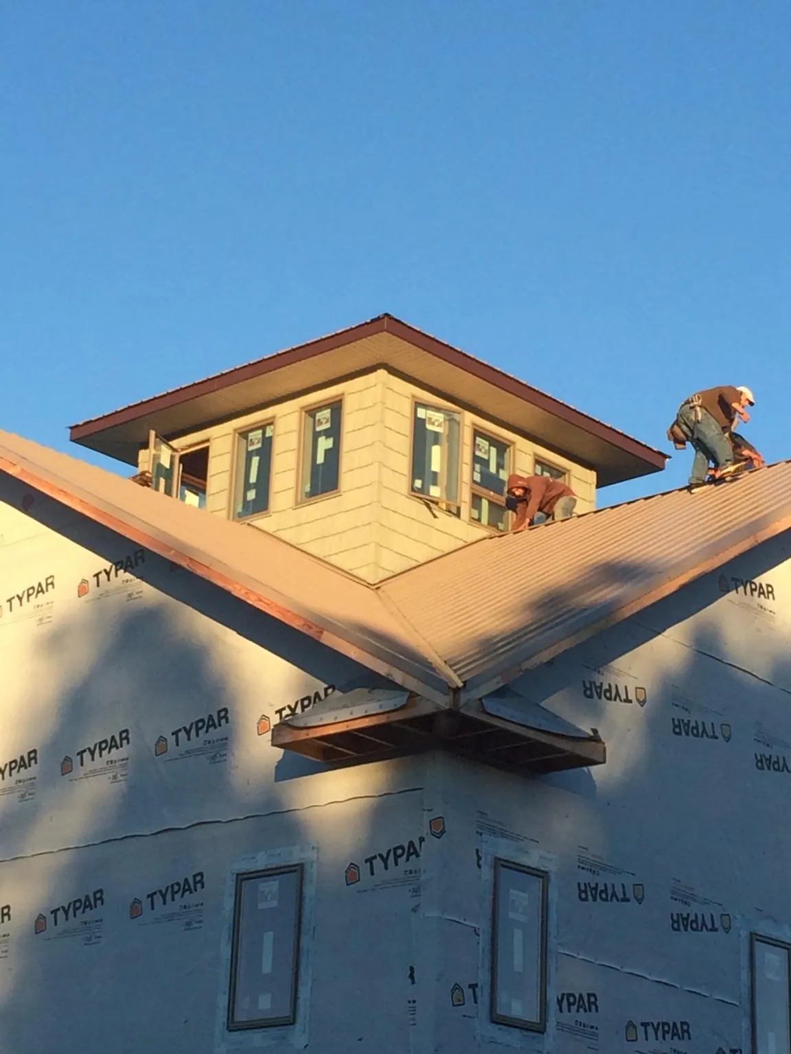 Roofers working around a rooftop cupola on a new metal roof at sunset — Roof Waterproofing in Noblesville by Roofing Brothers